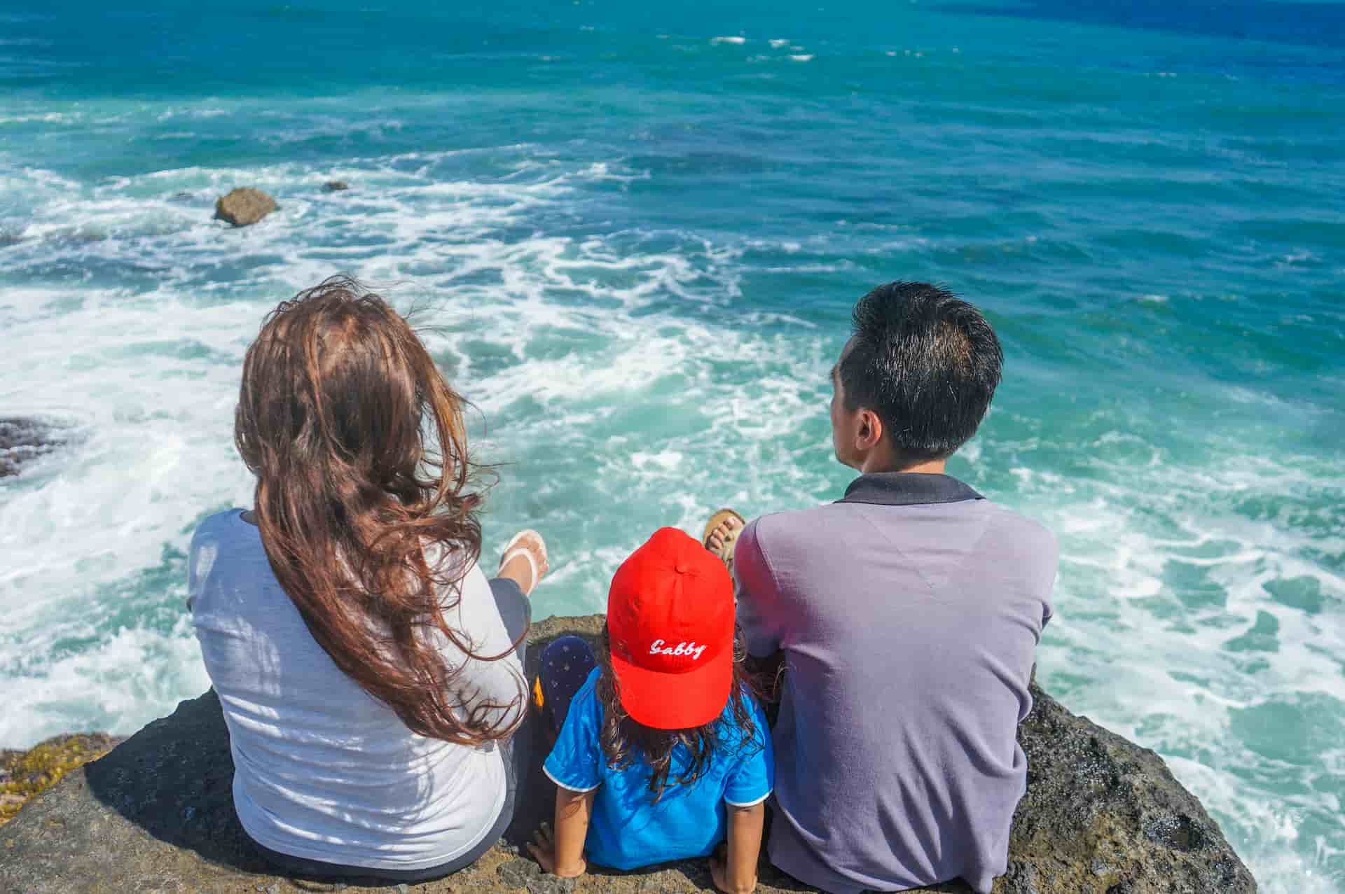Family sitting on a rock along the beach